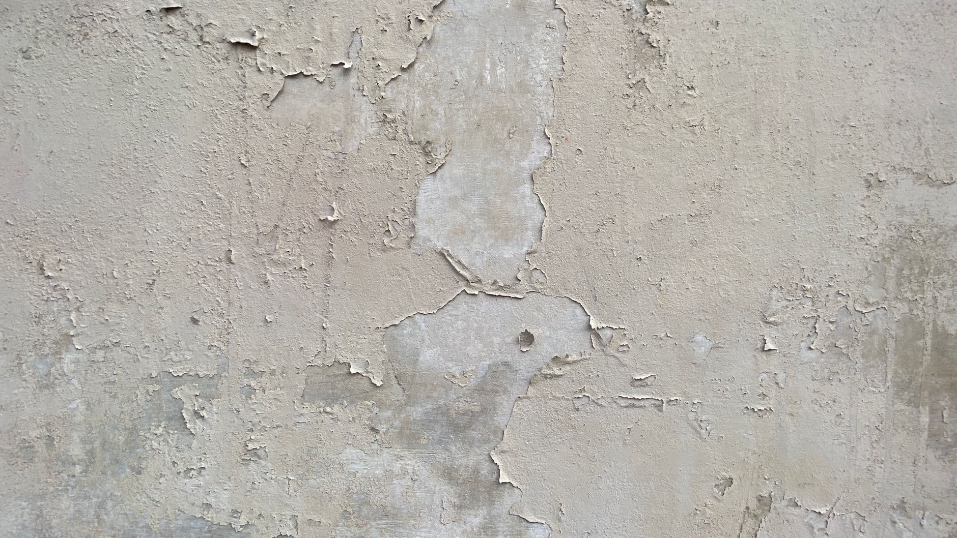 Beige muur met een afbladderende verflaag en kale, lichtere plekken eronder