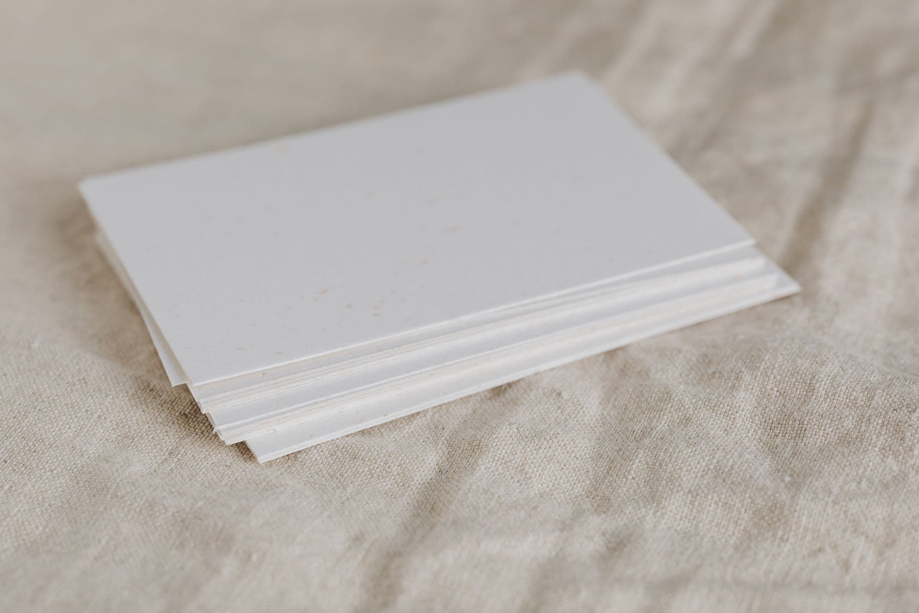 Stapel dikke witte vellen papier op een beige linnen ondergrond